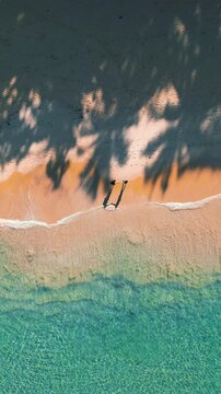 Aerial View of Couple Holding Hands on Beach with Waves