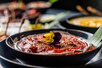 Roasted spicy chicken curry decorated with maroon and yellow flowers also with pomegranate served on a dinner table