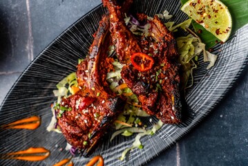 Spicy grilled lamb chops with vegetable salad, red chili,  tomato, and sauce