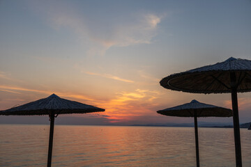 sunset on the beach with parasolls 
