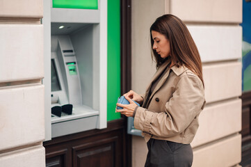 Businesswoman taking cash from wallet near atm