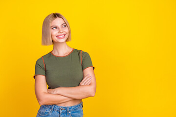 Obraz premium Photo of positive girl with bob hair dressed khaki t-shirt arms folded look at promo empty space isolated on yellow color background