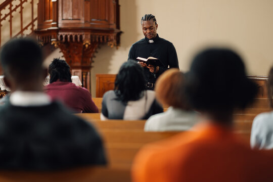 Young priest reading from the bible to his congregation