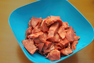 Tender pieces of veal rest in a vibrant blue cooking bowl, symbolizing the harmony of color and flavor. A culinary journey begins with this inviting preparation