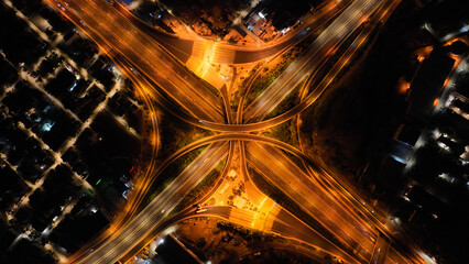 Obraz premium Aerial drone long exposure night shot of highway multilevel junction highway with light traffic leaving car headlights white and red trails
