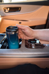 Gently hand placing a travel mug in the cars cup holder for convenience and comfort