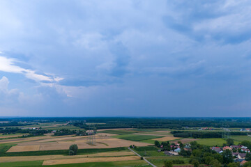 Obraz premium Aerial view of a lush green landscape with fields and scattered villages under a cloudy sky. Perfect for nature and rural themes.