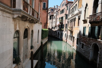 A small, enchanting canal is located between two buildings in Venice