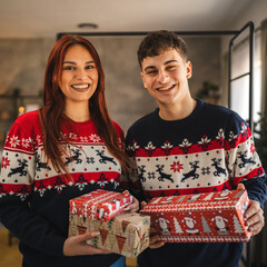 Portrait of couple exchanging holiday gifts in cozy festive setting