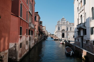 A small boat floats down a canal between historic buildings in Venice