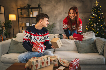 Obraz premium Girlfriend talk to her boyfriend while he wrap Christmas gift at home
