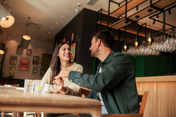 Joyful coffee conversation between friends in a cozy cafe surrounded by vibrant art on a sunny afternoon