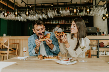 Enjoying delicious pizza together at a cozy restaurant with friends during a lively evening gathering