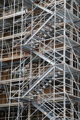 Obraz premium Sturdy steel staircase winds through a complex grid of scaffolding, illustrating the active construction process and the intricate support systems in place for building projects
