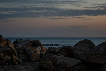 Sunset on the beach. Sunset on a cloudy sky. Large stones on the beach.