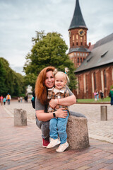 A little Caucasian toddler girl with a young mother travels in Kaliningrad near the Cathedral in the city center.