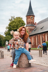 A little Caucasian toddler girl with a young mother travels in Kaliningrad near the Cathedral in the city center.