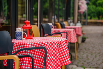 Red checkered cloth on the tables on the veranda of an outdoor cafe in summer.
