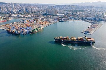 Large container ship with tug boats assisting by pulling fully loaded container ship to dock to...