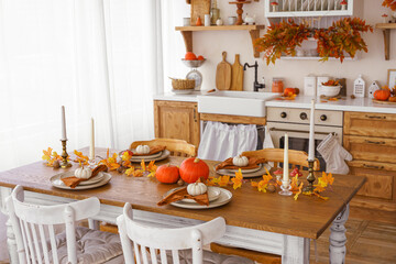 Kitchen, dinning table decorated with pumpkin, candle and leaves for Halloween, Thanksgiving day