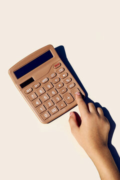 Hand pressing a button on a brown calculator
