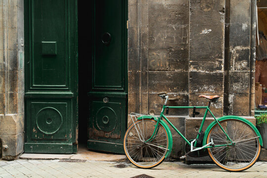 Vintage green bicycle by old weathered doors in Bordeaux