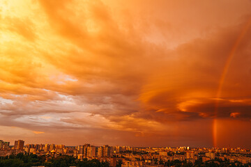 View of rainbow over buildings. Orange sky.
