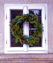 Homemade DIY christmas wreath decorated pine cones and fir trees on a window of old village house from 18 th centruy, Czechia.