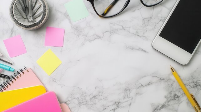 A workspace with stationery, glasses, and a smartphone on a marble surface.