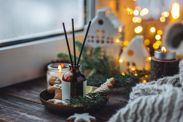 Christmas home aromatherapy. Aroma diffuser with pine extract, organic essential oil, cedar and spruce cone, cinnamon, anise, vanilla scent, candles, wooden table. Cozy atmosphere, winter inspiration
