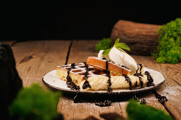 Sweet dessert waffles. Served with ice cream. Belgian waffles with banana, ice cream and chocolate on top. Delicious dessert for tea time. Mint on top of dessert. Cooking process.