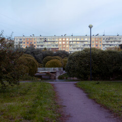 Soviet-style panel apartment buildings. A park with a small pond and a metal bridge.