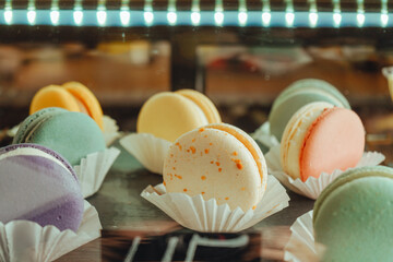 Sweet food concept. Different color macarons on plate in marketplace. French dessert assortment....