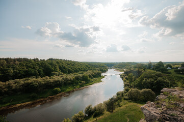 Obraz premium Serene River Valley Landscape Under a Brush of Fluffy Clouds