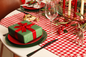 Table setting with Christmas decorations and gift in living room