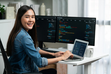 Young Asian in IT developer looking at camera to present with online information on pc with coding...
