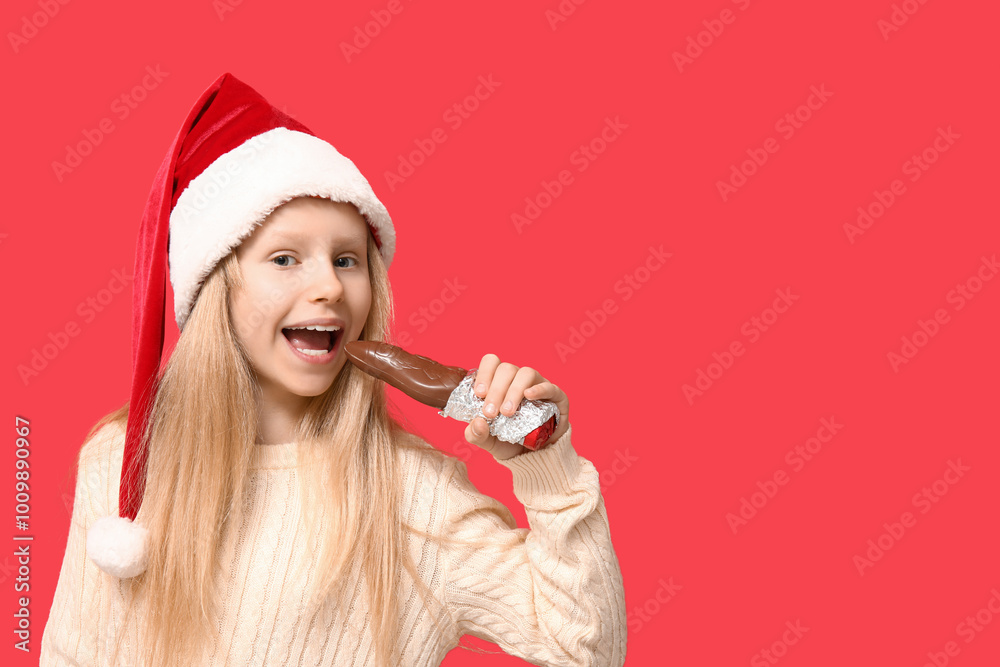 Sticker Cute little girl eating chocolate Santa Claus on red background