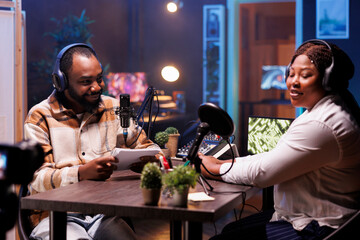 Content creators are live streaming online vlogs from home using digital camera. African American vloggers are recording podcasts with professional audio equipment for posting on social media.