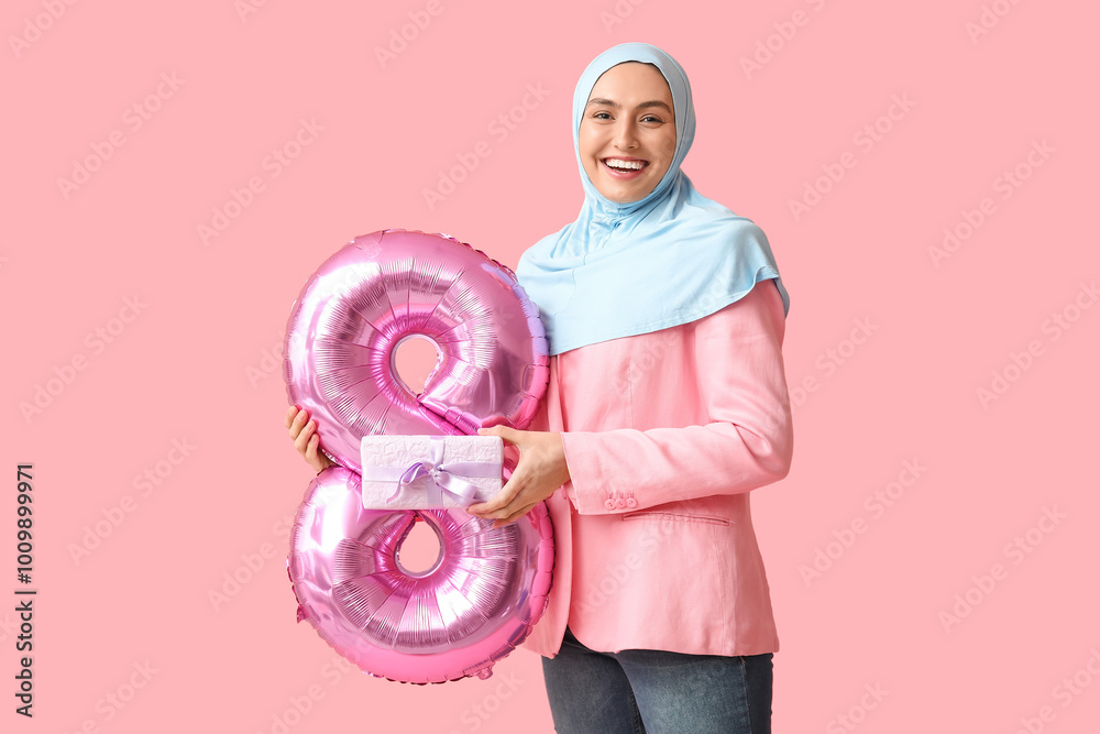 Poster Beautiful young Muslim woman in hijab with pink air balloon in shape of figure 8 and gift box on color background. International Women's Day