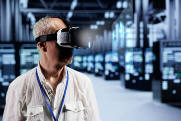 Old cloud computing business executive immersed in virtual reality at data center, doing equipment maintenance. Repairman using VR headset to optimize server rigs performance, checking code lines