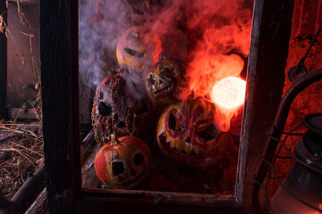 art scary Halloween with pumpkins and an old kerosene lamp in a red light preparation for the celebration in a dark room 