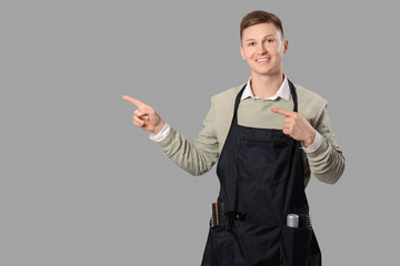 Male barber pointing at something on grey background