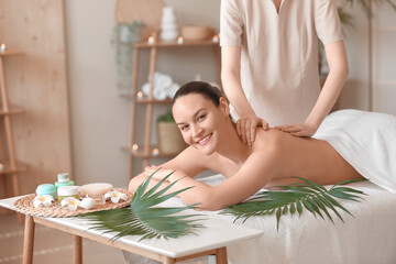 Happy young woman getting back massage in spa salon