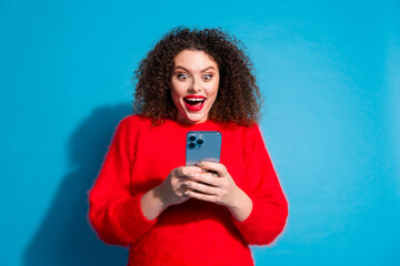 Photo portrait of attractive young woman excited hold gadget dressed stylish red clothes isolated on blue color background