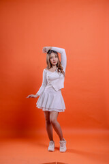 full body beautiful asian woman white top standing elegant hands above head and right isolated orange background. for fashion, beauty, advertising concept,