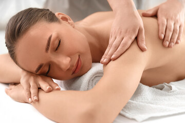 Beautiful young woman getting shoulder massage in spa salon, closeup