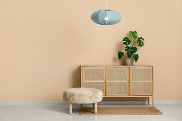 Stylish living room with chest of drawers, houseplant, pouf and hanging lamp