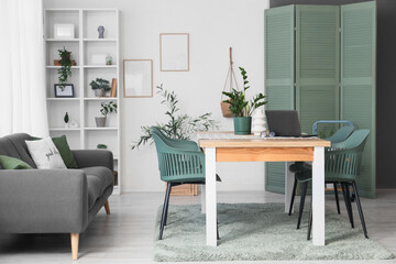 Interior of light dining room with table, sofa and folding screen