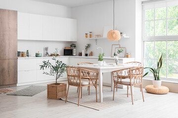 Interior of light dining room with table and wicker chairs