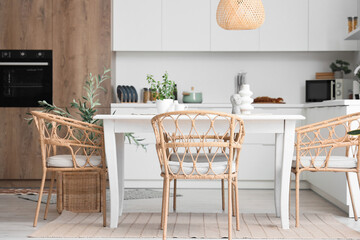 Interior of light dining room with table and wicker chairs